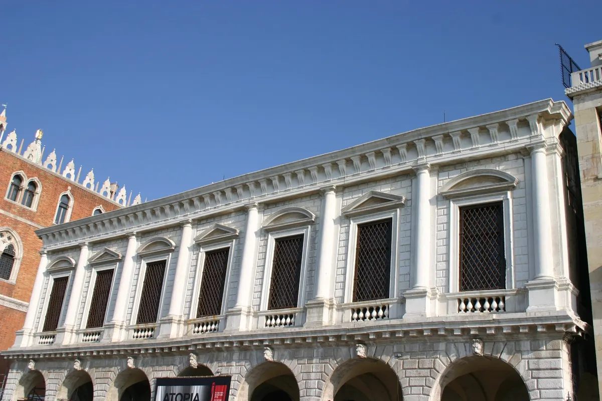 The white stone front of the New Prisons with barred windows, columns and a row of carved heads above the arcade.
